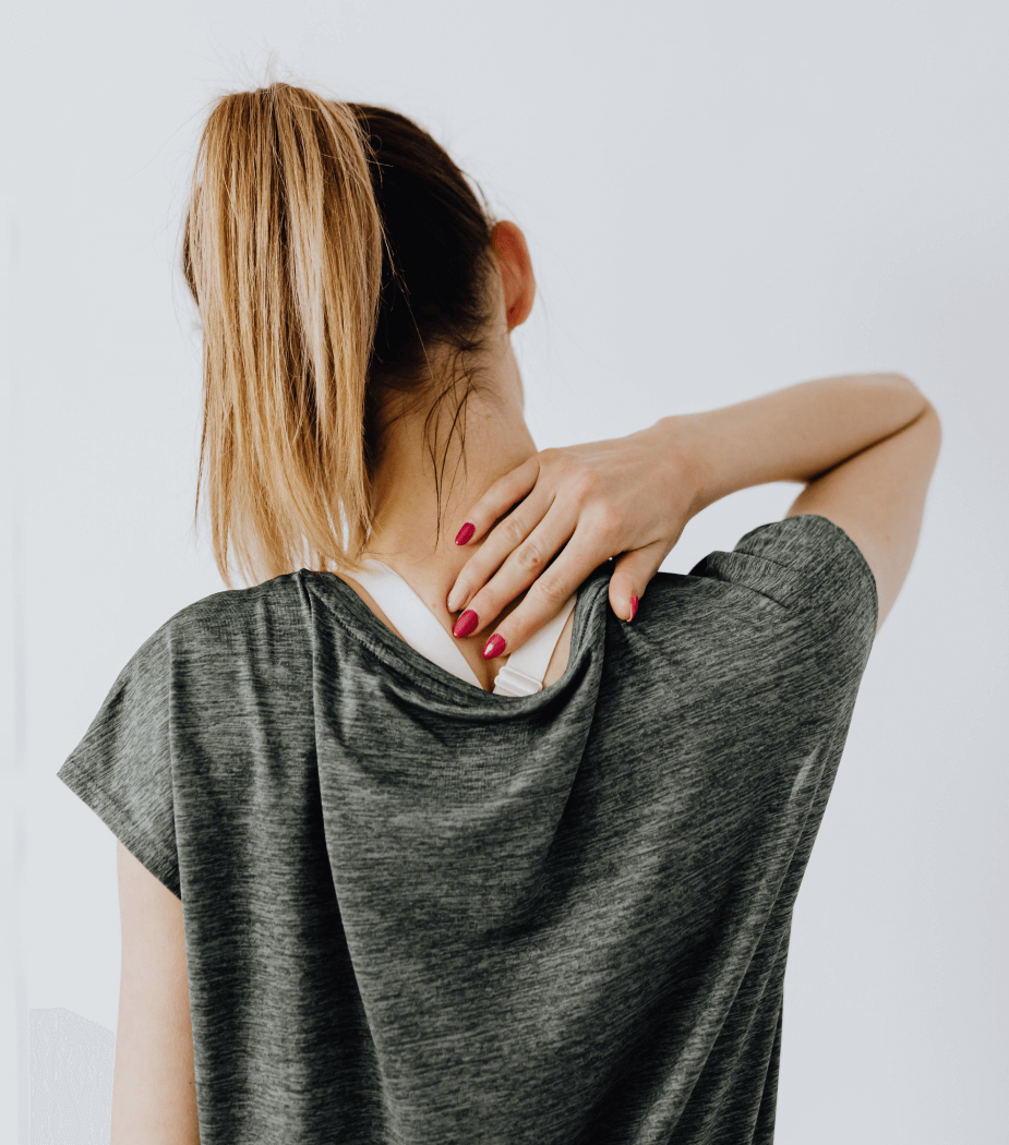 A woman touching the back of her neck in pain.