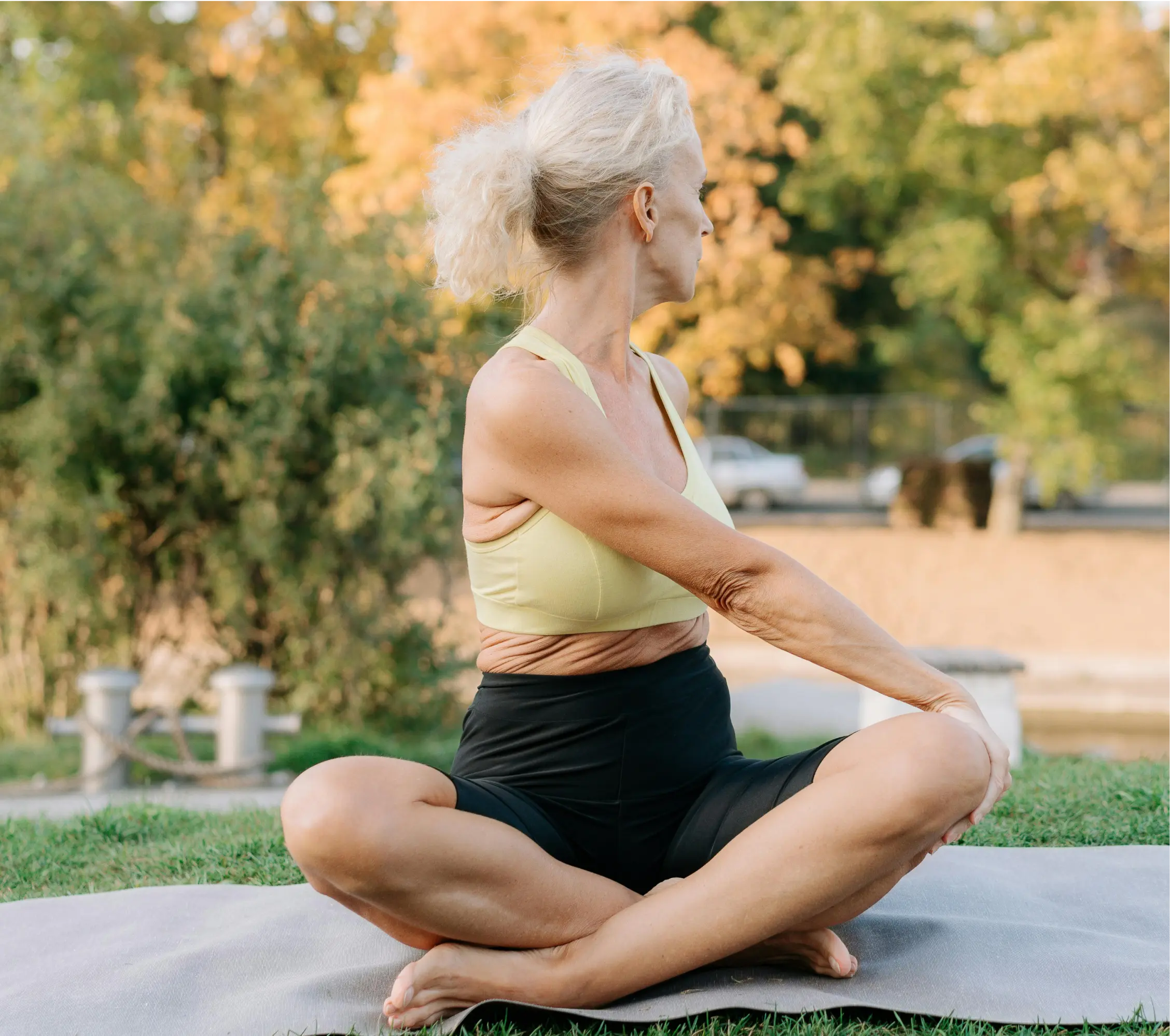 An older woman sitting cross-legged twisting to the side.