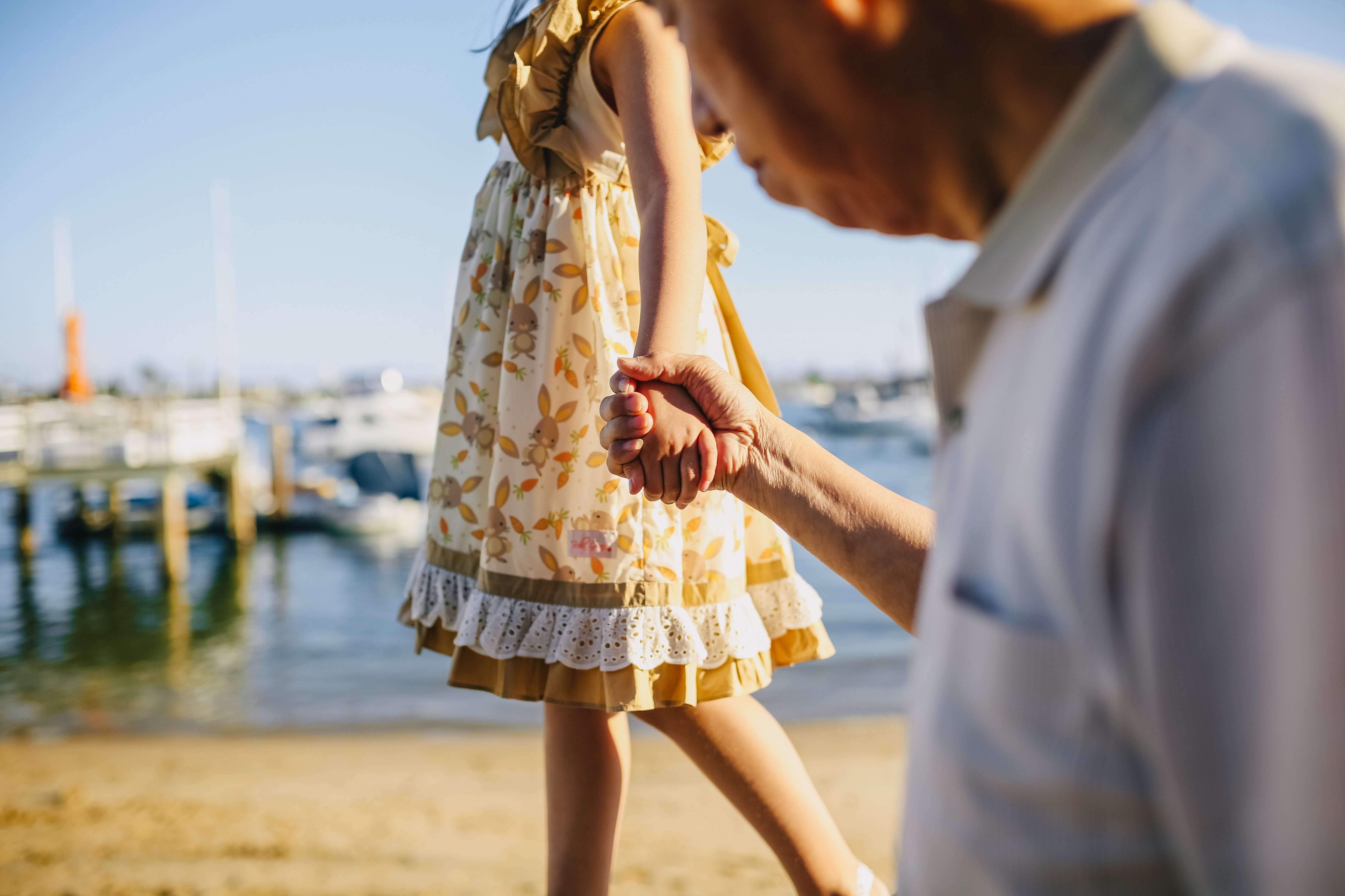 A young girl and an old man holding hands.